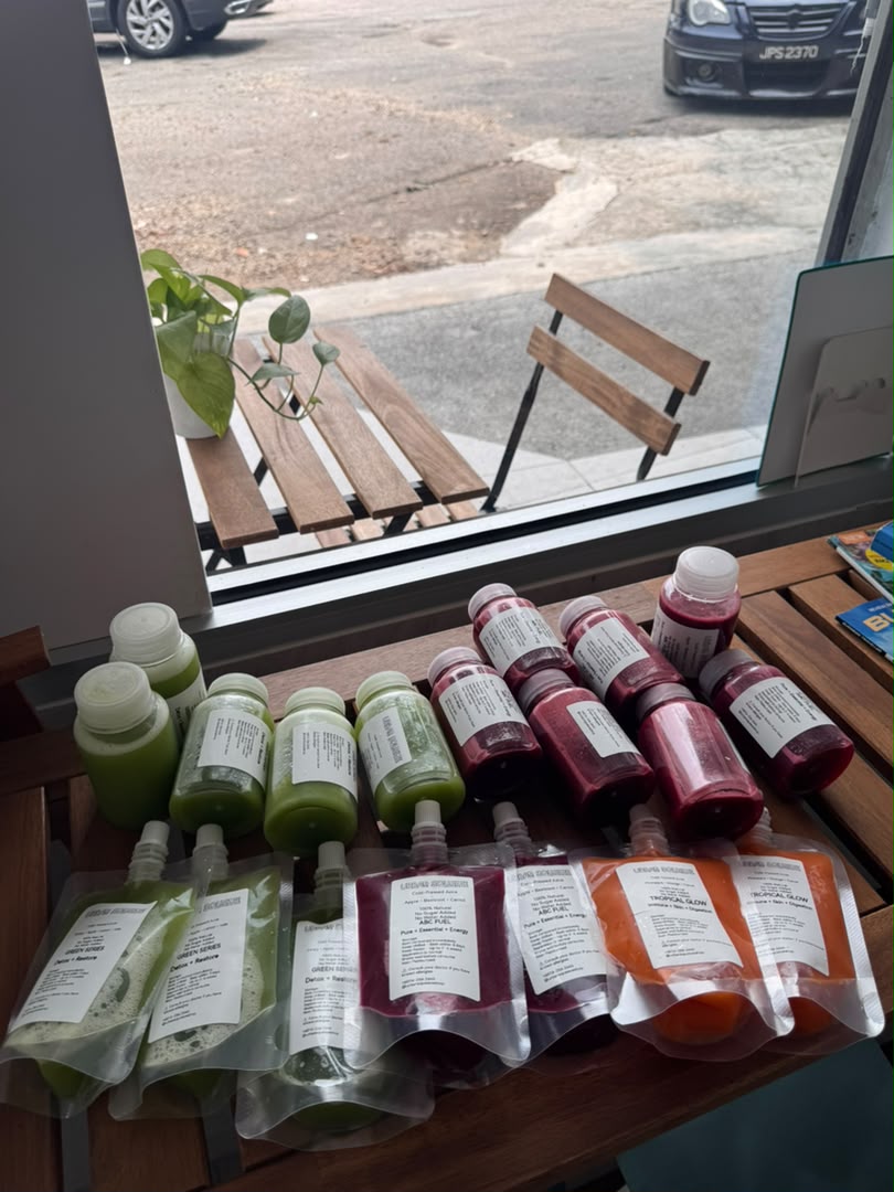 Green and red juice bottles with green, red and orange juice pouches displayed on a wooden table