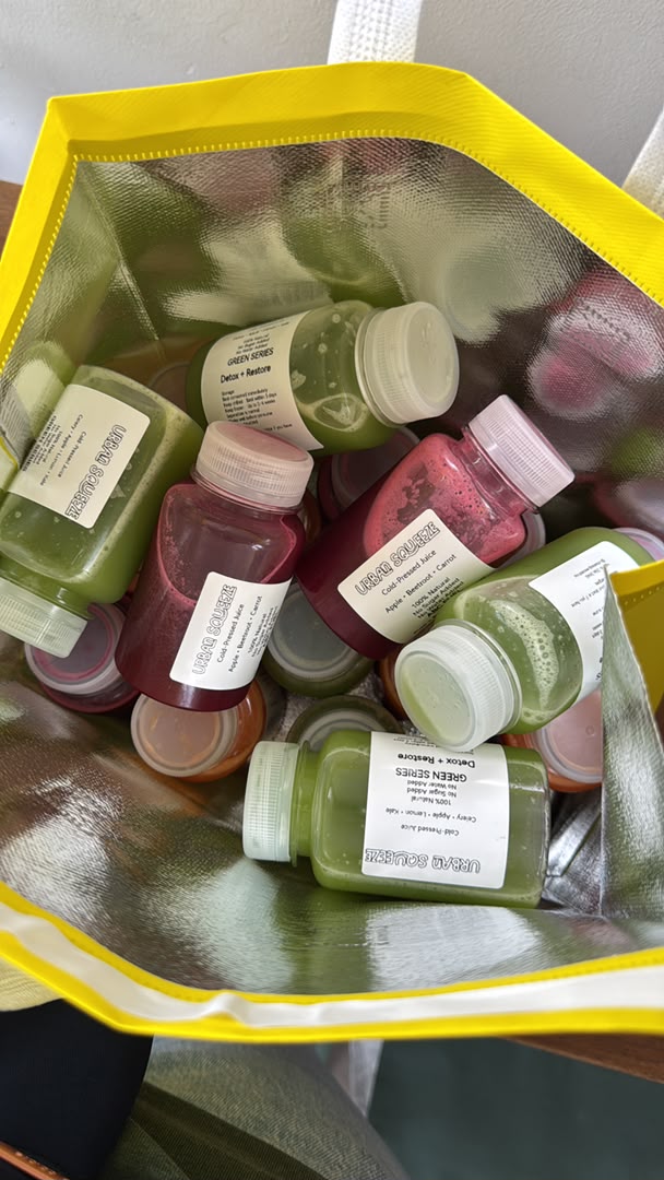Mixed cold-pressed juice bottles packed in a yellow insulated bag