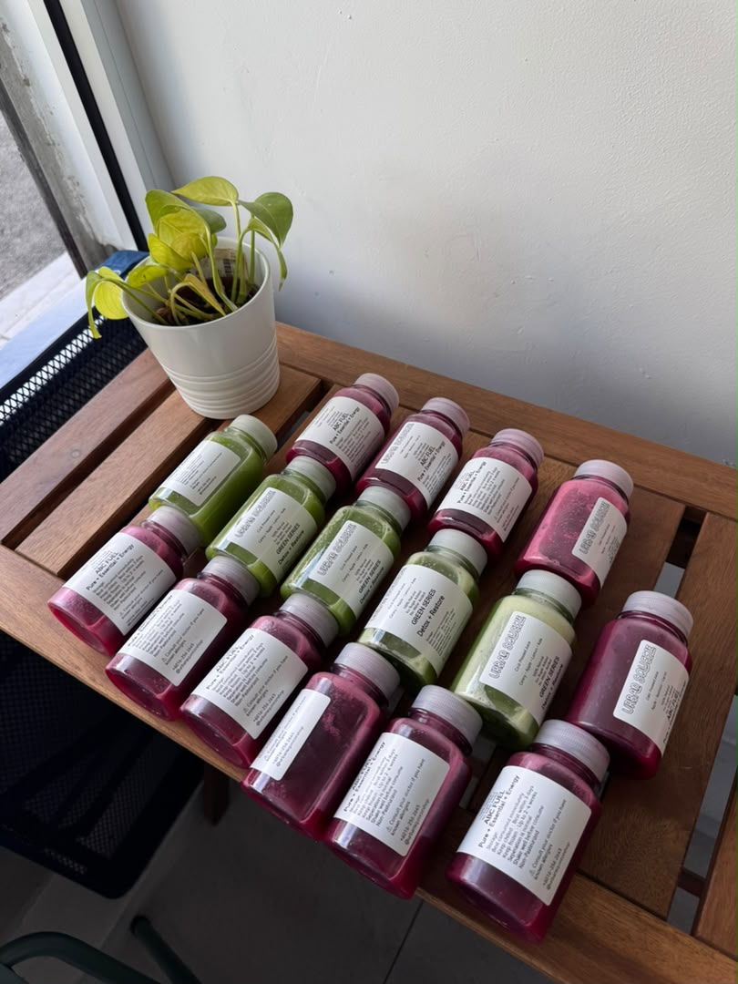 Red ABC Fuel and green Green Series juice bottles arranged in a grid on a wooden table